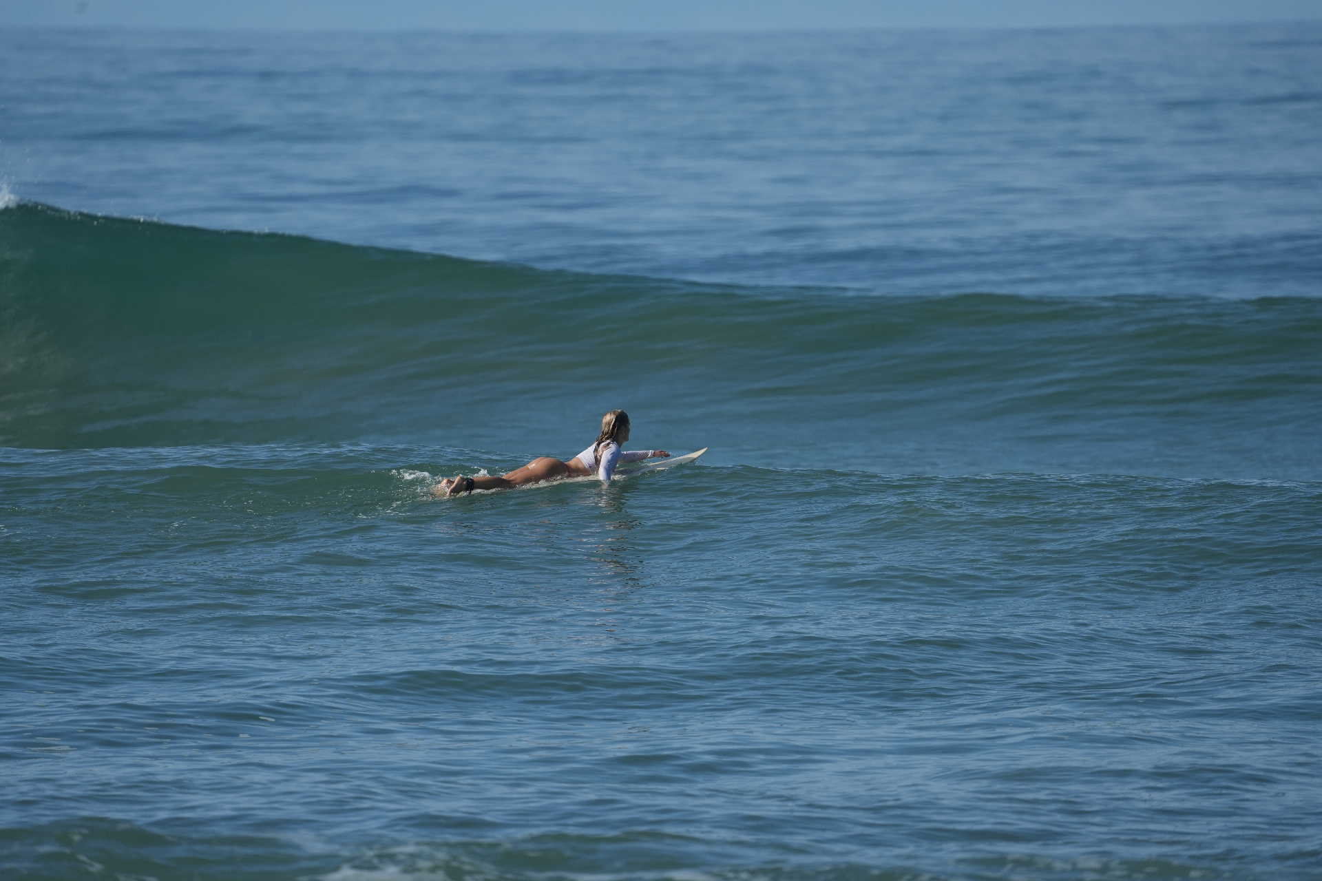 A surfer paddling into a clean Santa Teresa wave — the smooth, patient glide intermediates chase