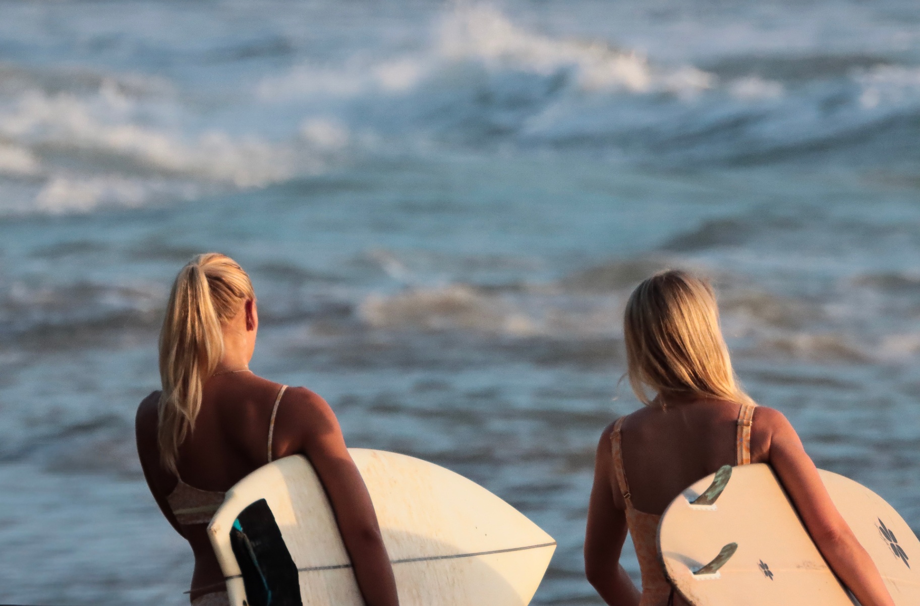 Two surfers walking down to the water in golden Santa Teresa light