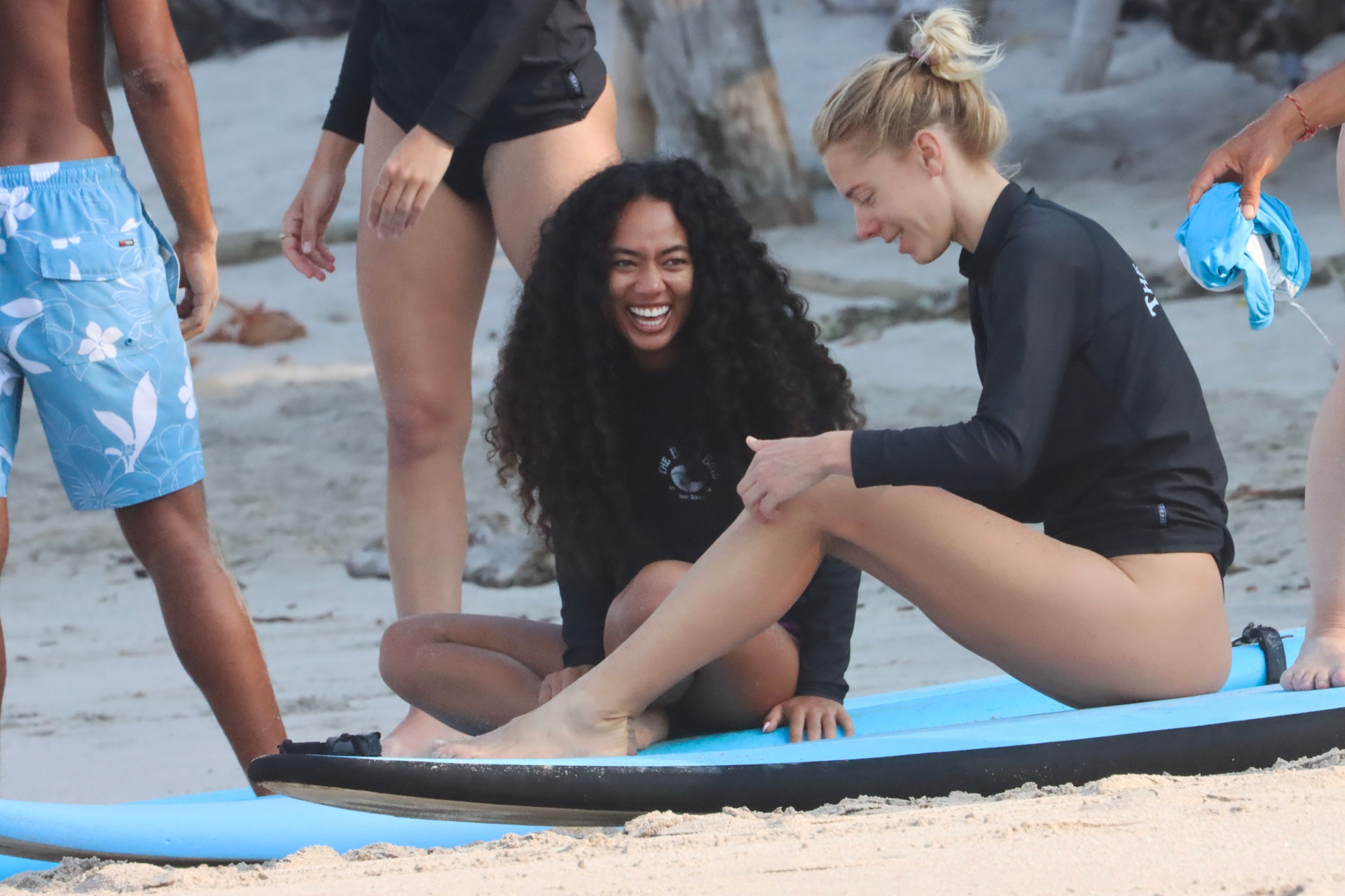 Two friends cracking up together on the sand after a session