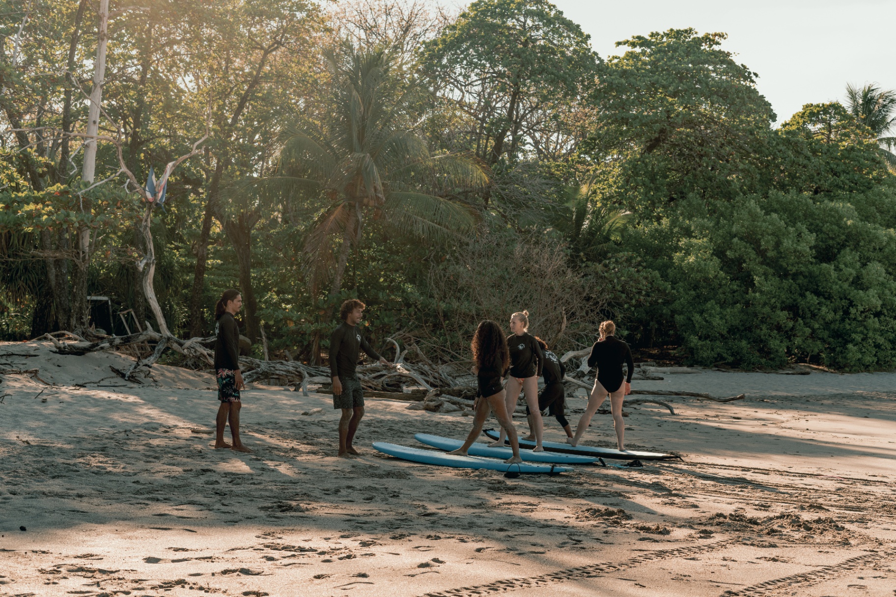 The Beach Boys instructors practicing surf stance on the sand with beginners at Santa Teresa before paddling out